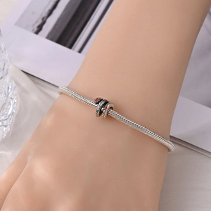 Detailopname van een zilveren slangenarmband met rode strassteentjes om de pols