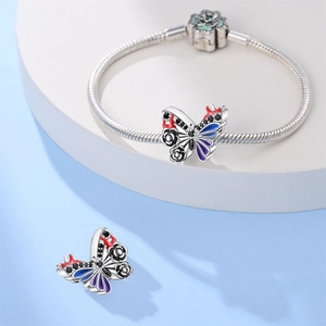 Detail van zilveren vlinderbedeltjes met gekleurd emaille en rozenpatronen op een slangenketting