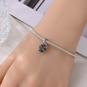 Detail van zilveren slangenketting armband met vintage schedelbedeltje om de pols