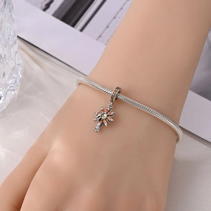 Dettaglio ciondolo sole con zirconi arancio e bianchi su bracciale a catena snake