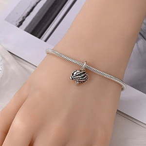 Macro-opname van skelethand-hartbedeltje aan slangenarmband met rode edelstenen