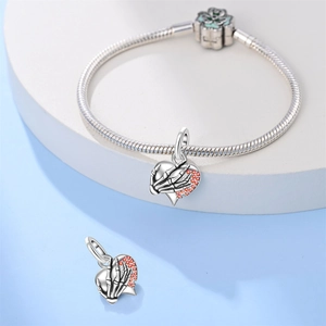 Detail van zilveren skelethand bedel met hart en oranje stenen op een slangenketting