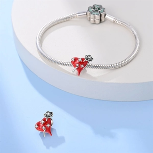 Detail van zilveren slangenarmband met rode emaille rooshartbedels en een bloemvormige sluiting