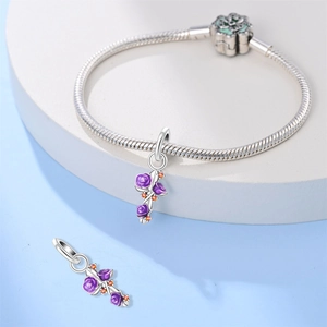 Detail van zilveren slangenarmband met paarse emaille rozenbedeltjes op een blauwe sokkel