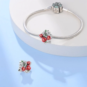 Detail van zilveren slangenarmband met rode emaille rooshangers en zirkoonstenen