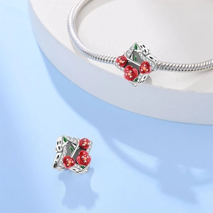 Detail van zilveren roos-bedeltje met rood emaille en zirkoon op een slangenarmband