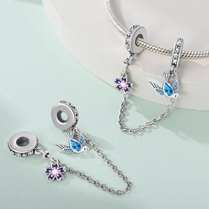 Macro shot of silver swallow and flower charm safety chain with colorful gemstones
