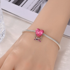 Detail von Silber-Schlangenarmband mit rosa Emaille-Herz und schwingendem Paar-Anhänger