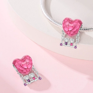 Detail eines rosa Emaille Herz-Charms mit zwei Personen auf einer Schaukel und Zirkonia