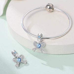 Macro shot of a silver bow charm with blue heart stone on a round bangle clasp