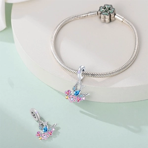 Macro detail of silver snake chain bracelet with floral charms and green enamel clasp