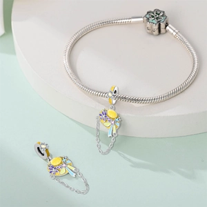 Detail of silver snake chain bracelet featuring yellow sun hat charms with floral accents