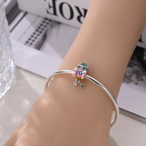 Close-up of a silver bracelet with a pink spacecraft charm and blue heart zircon