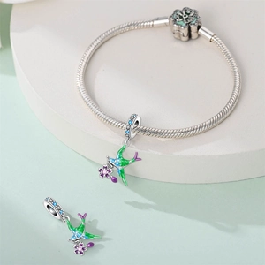 Close-up of hummingbird charm with teal enamel and purple flower on silver snake chain