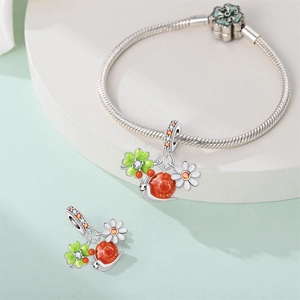 Macro detail of silver snail and daisy charms on a snake chain bracelet with zircons