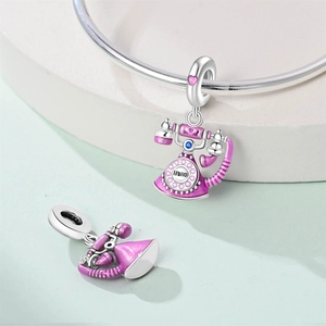 Macro detail of retro pink enamel phone charm with Hello engraving and blue gemstone