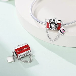 Detail of silver camera charm with red enamel, butterfly tag and engraved inscriptions