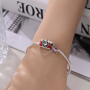 Silver open bangle with camera charm and pink butterfly pendant on wrist
