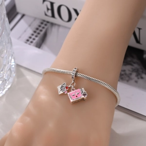 Close-up of a silver charm bracelet featuring a pink enamel mailbox and envelope pendant