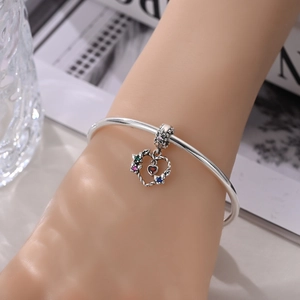 Detailed view of silver heart charm with colorful zircon inlay on a sleek metal bangle