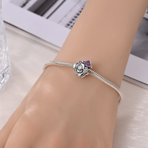 Detailaufnahme des Schlangenarmbands mit silberner Rose und pinkfarbenem Herz-Charm