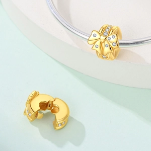 Goldener Schleife-Charm mit Herz-Stein auf silbernem Schlangen-Armband für Damen
