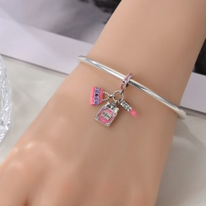 Detailed close-up of silver bangle with pink handbag, perfume, and lipstick charms