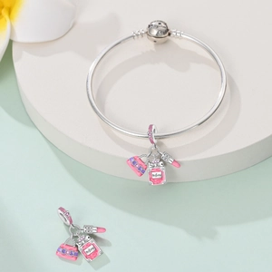 Detailed macro of silver charm bracelet with pink handbag and perfume bottle pendants