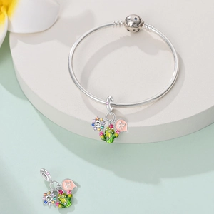 Macro detail of flamingo sunflower charms on a silver bangle with colorful enamel accents