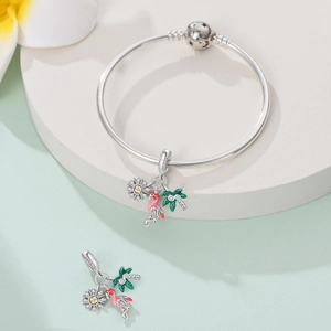 Close-up of flamingo and palm tree pendants on a silver snake chain bracelet