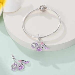 Macro detail of silver camera, handbag and high heel charms on a snake chain bracelet