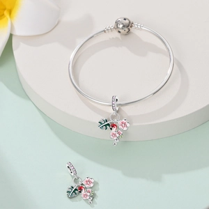 Silver snake chain bracelet featuring pink flamingo and green leaf tropical charms