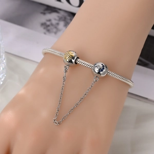 Close-up of beaded safety chain charm with sun and moon motifs on a silver bracelet