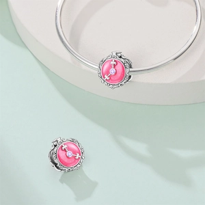 Macro detail of vintage clock charm with pink enamel and purple zircon on silver bracelet