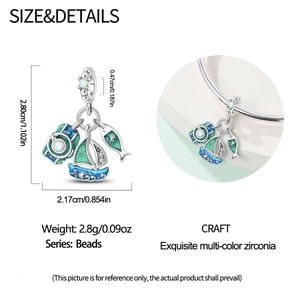 Detail of travel-themed nautical charms with camera, sailboat, and fish on a DIY bracelet