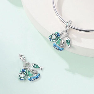 Detailed macro view of nautical charms featuring sailboats and teal enamel on a silver bracelet