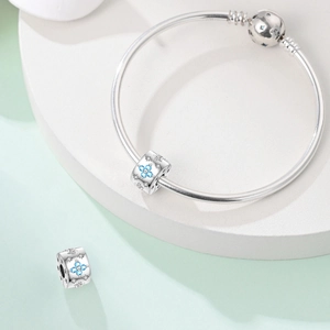 Makroaufnahme von Silber-Schlangenarmband mit blauem Kleeblatt-Charm und Stern-Verschluss