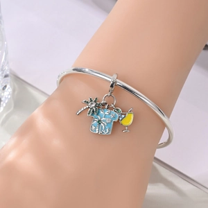 Macro view of silver bracelet with palm tree, aloha shirt and cocktail charm pendants