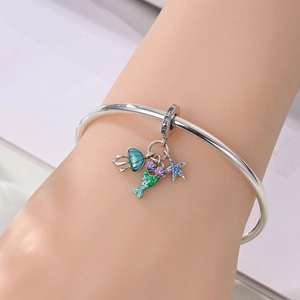 Detail of silver mermaid tail, starfish and shell charms on an open bangle bracelet