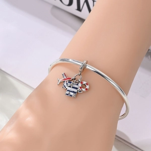Detailed close-up of nautical silver charm bracelet featuring airplane and lifebuoy charms