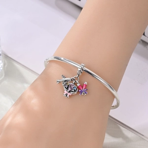 Silver open bangle with pink teardrop zircon mask and purple bow charm on hand