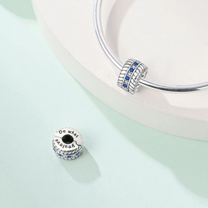 Detail eines Silber-Charms mit blauen Steinen und 'Do what you love' Gravur für Armbänder