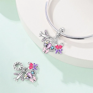 Detail of travel themed charms with airplane, heart and champagne cups on a silver bracelet