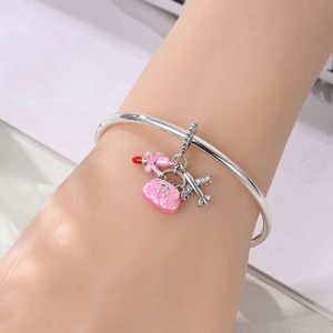 Silver charm bracelet featuring a pink handbag, lipstick, and crystal plane on a wrist