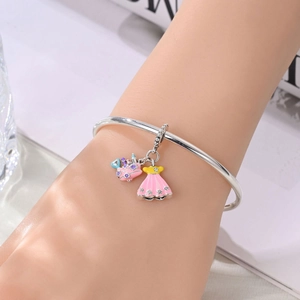 Detail of silver bracelet featuring pink enamel dress and castle heart pendants on wrist