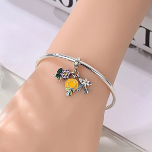 Detail of travel themed silver bangle featuring enamel hat, plane and flower charms