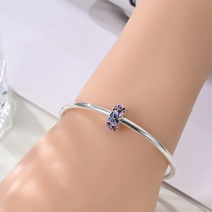 Nahaufnahme des silbernen Blumenanhängers mit lila Emaille am schlanken Armband
