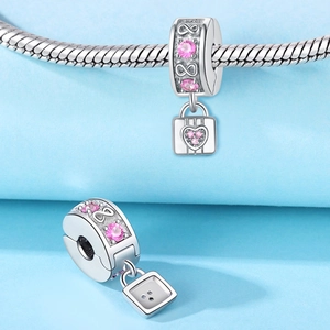 Makroaufnahme von Silber-Charm mit rosa Zirkon-Herzschloss und Unendlichkeitssymbol