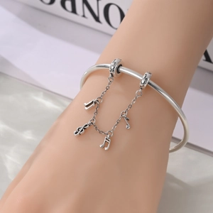 Dettaglio del bracciale con ciondoli musicali in argento con note e chiavi di violino