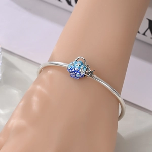 Close-up of silver-plated open bangle with blue sea shell and starfish charms on a wrist